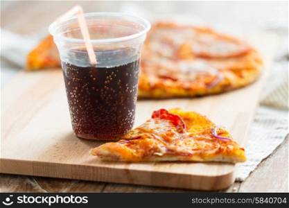 fast food, italian kitchen and eating concept - close up of pizza with cup of coca cola drink on wooden table