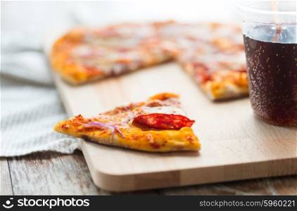 fast food, italian kitchen and eating concept - close up of pizza slice and carbonated drink on wooden table