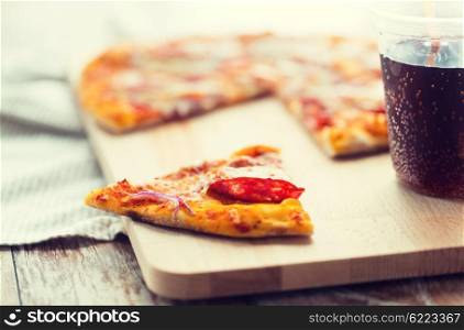fast food, italian kitchen and eating concept - close up of pizza slice and carbonated drink on wooden table