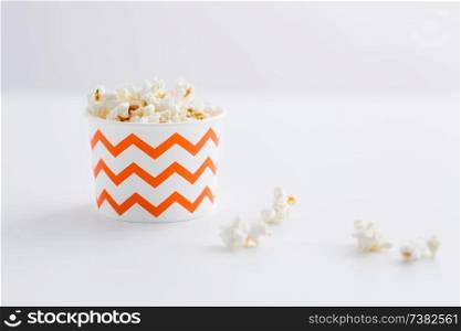 fast food, junk-food and unhealthy eating concept - close up of popcorn in disposable paper cups with zig zag pattern. close up of popcorn in disposable paper cups