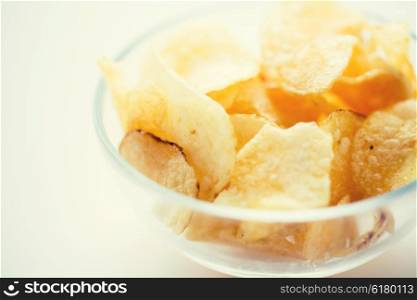fast food, junk-food, cuisine and eating concept - close up of crunchy potato crisps in glass bowl
