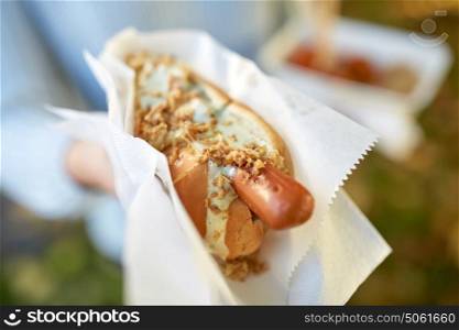 fast food, people and unhealthy eating concept - close up of hand with hot dog. close up of hand with hot dog
