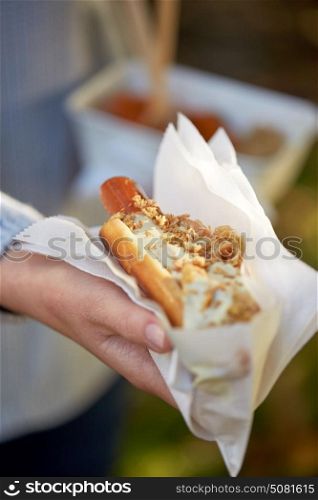 fast food, people and unhealthy eating concept - close up of hand with hot dog. close up of hand with hot dog