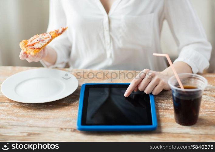 fast food, people, technology and diet concept - close up of woman hands with tablet pc computer, pizza and coca cola counting calories at table