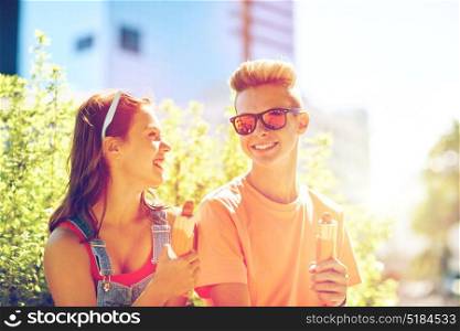 fast food, summer and people concept - happy teenage couple eating hot dogs sitting on city street bench. happy teenage couple eating hot dogs in city