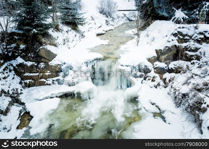 Fast river with waterfall in Austrian Alps at snowy day