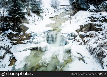 Fast river with waterfall in Austrian Alps at snowy day