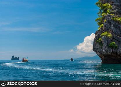 fast wooden Thai boats with a motor in the Andaman Sea near beautiful rocks