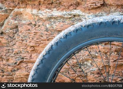 fat bike wheel covered by dust, mud and snow against sandstone canyon wall