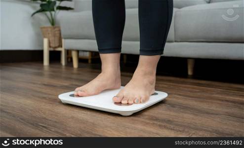 Fat diet and scale feet standing on electronic scales for weight control. Measurement instrument in kilogram for a diet control