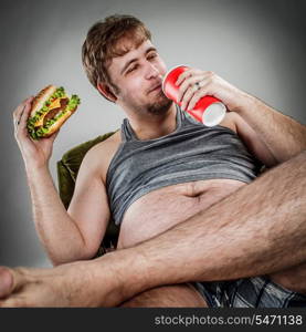 Fat man eating hamburger seated on armchair. Style fast food.