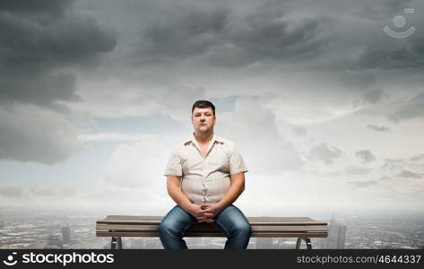Fat man. Fat man sitting on bench and looking in camera