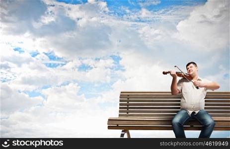 Fat man. Fat man sitting on bench and playing violin