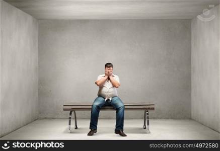 Fat man. Fat man sitting on bench closing eyes with hands