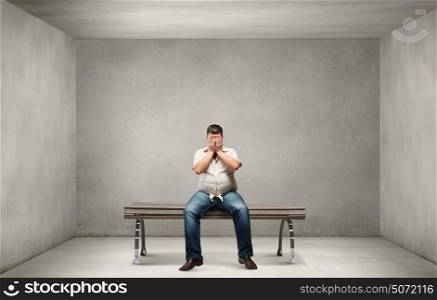 Fat man. Fat man sitting on bench closing eyes with hands