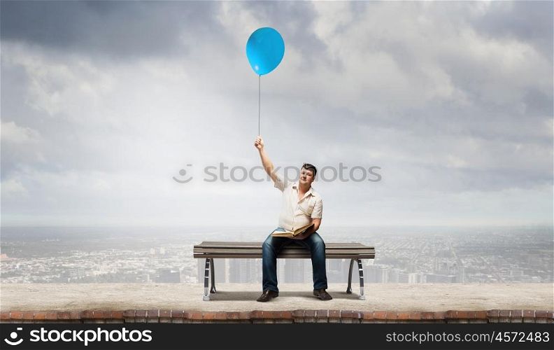 Fat man. Fat man sitting on bench with book and balloon in hand
