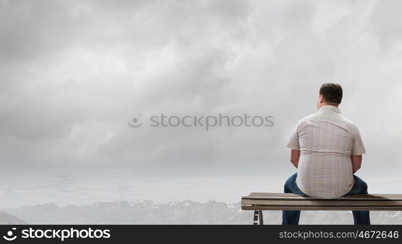 Fat man. Fat man sitting on bench with his back and looking away