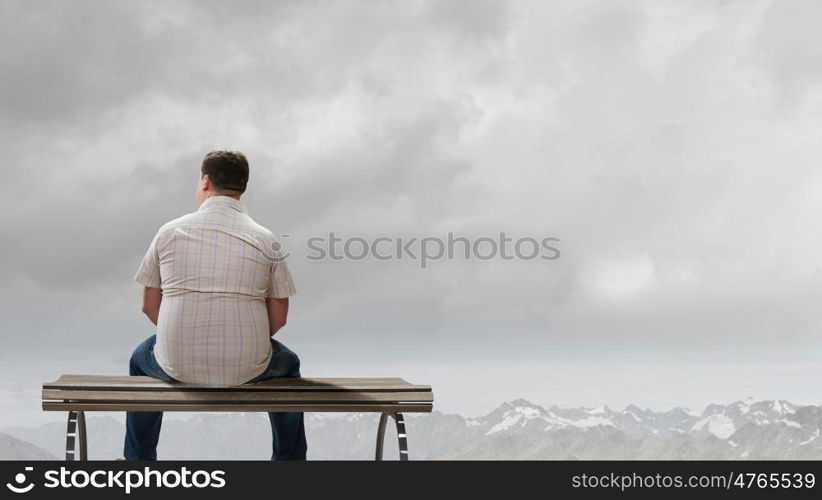 Fat man. Fat man sitting on bench with his back and looking away