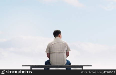 Fat man. Fat man sitting on bench with his back and looking away