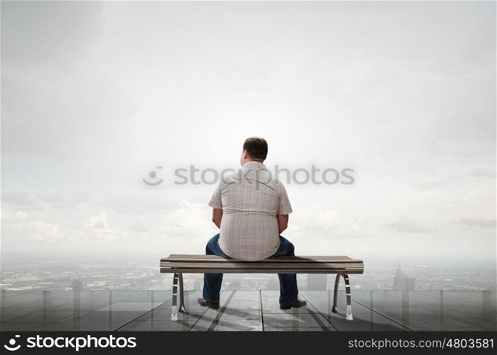 Fat man. Fat man sitting on bench with his back and looking away