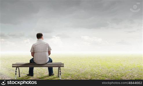 Fat man. Fat man sitting on bench with his back and looking away