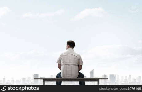 Fat man. Fat man sitting on bench with his back and looking away