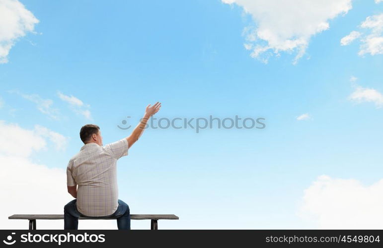 Fat man. Fat man sitting on bench with his back and pointing away