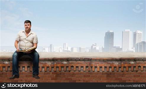Fat man. Fat man sitting on building top with book in hands