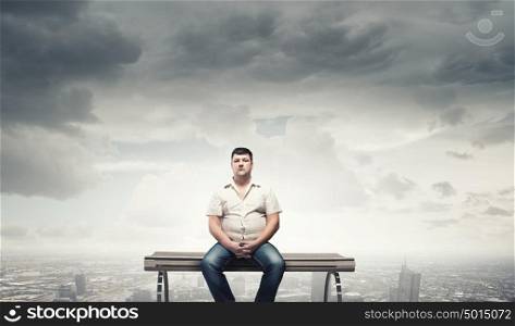 Fat man sitting on bench and looking away. Fat man