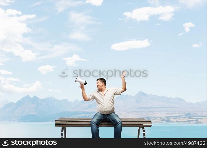 Fat man sitting on bench and screaming in megaphone. Fat man