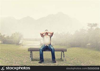 Fat man sitting on bench closing eyes with hands. Fat man