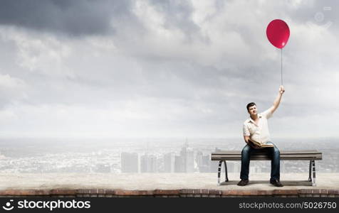 Fat man sitting on bench with book and balloon in hand. Fat man
