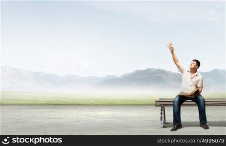 Fat man sitting on bench with book and reaching hand. Fat man