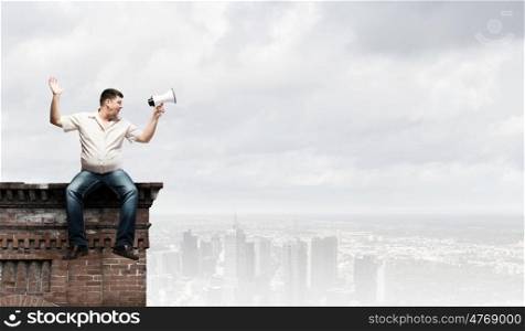 Fat man sitting on roof edge and screaming in megaphone. Fat man