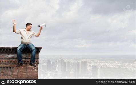 Fat man sitting on roof edge and screaming in megaphone. Fat man