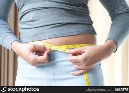 Fat woman hand holding measurement tape on her belly fat. woman diet lifestyle and build muscle concept.