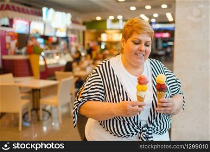 Fat woman holding ice cream in fastfood mall restaurant, unhealthy food. Overweight female person with ice-cream, obesity problem. Fat woman holding ice cream in fastfood restaurant