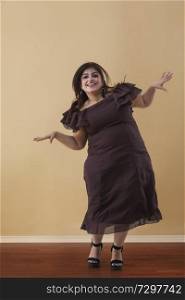 Fat woman in a long brown dress dancing on high heels
