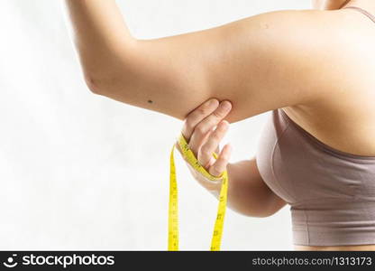 fat woman, woman hand pinching on her excessive fat arm with measure tape, woman diet lifestyle concept