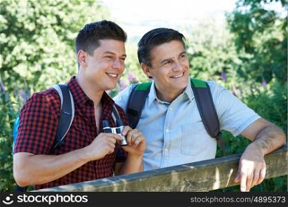 Father And Adult Son Hiking In Countryside Looking Through Binoculars