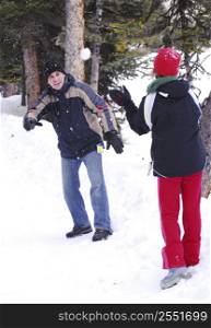 Father and chid throwing snowballs at winter park