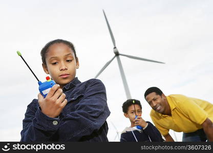 Father and children (7-9) playing with walky-talkies at wind farm