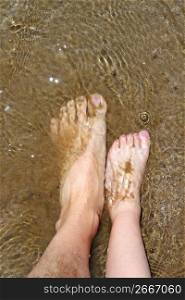 father and children feet on summer sand beach shore wavy water