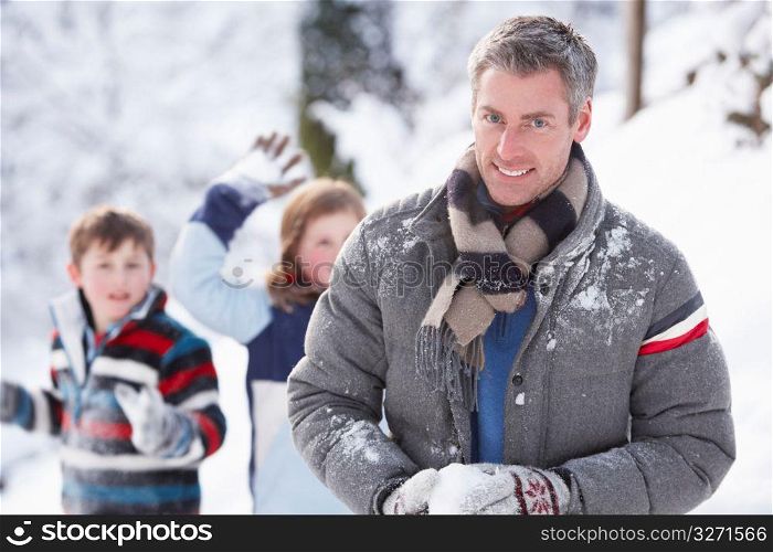 Father And Children Having Snowball Fight In Winter Landscape