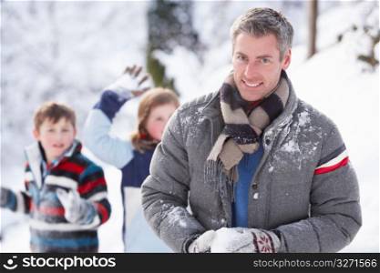 Father And Children Having Snowball Fight In Winter Landscape