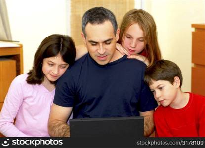 Father and children looking into a portable computer at home
