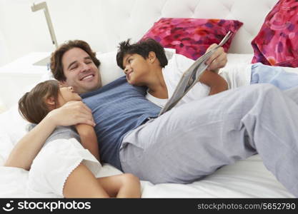 Father And Children Relaxing In Bed Together