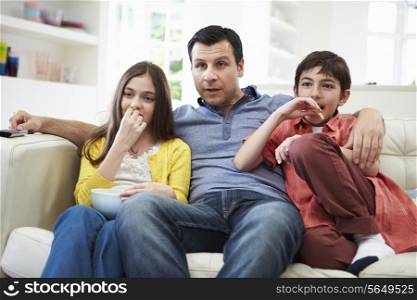 Father And Children Sitting On Sofa Watching TV Together