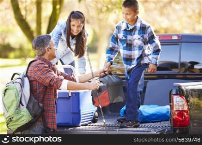 Father And Children Unpacking Truck On Camping Holiday
