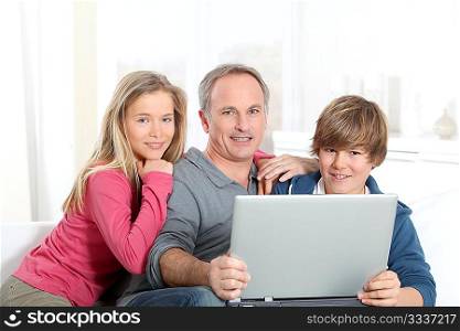 Father and children using laptop computer at home